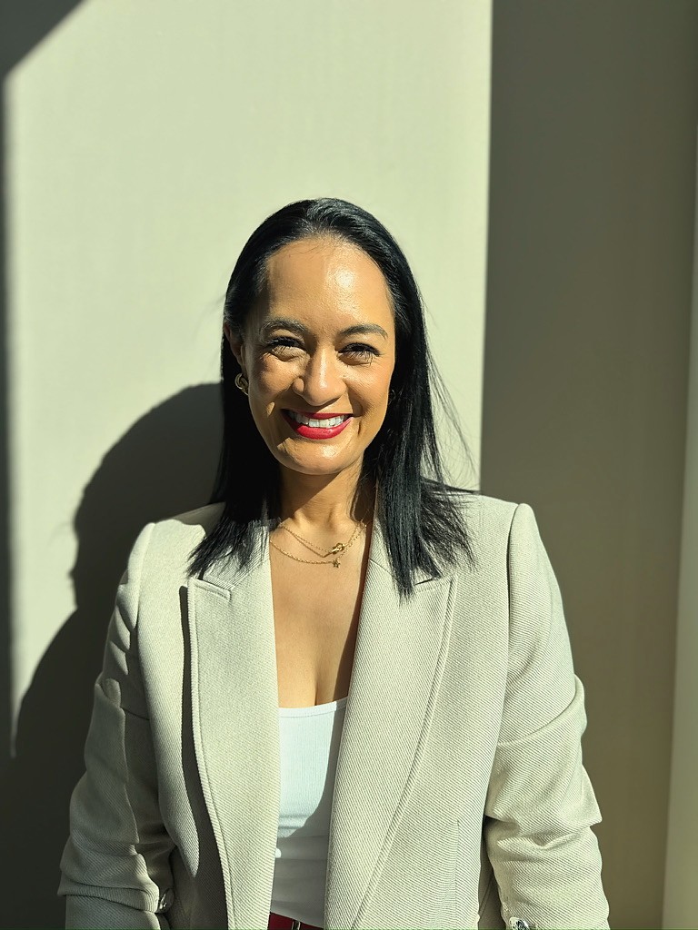 Anne Maxwell smiling against a sunlit wall